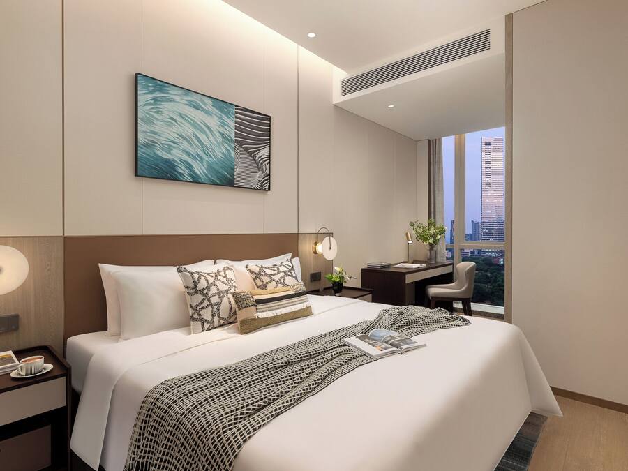 Quarto de hotel moderno com uma cama grande, uma escrivaninha e vista para a cidade.