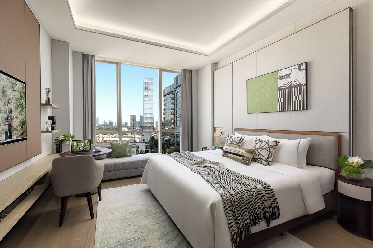 A modern hotel room with a large bed, a seating area, a TV, and a city view.