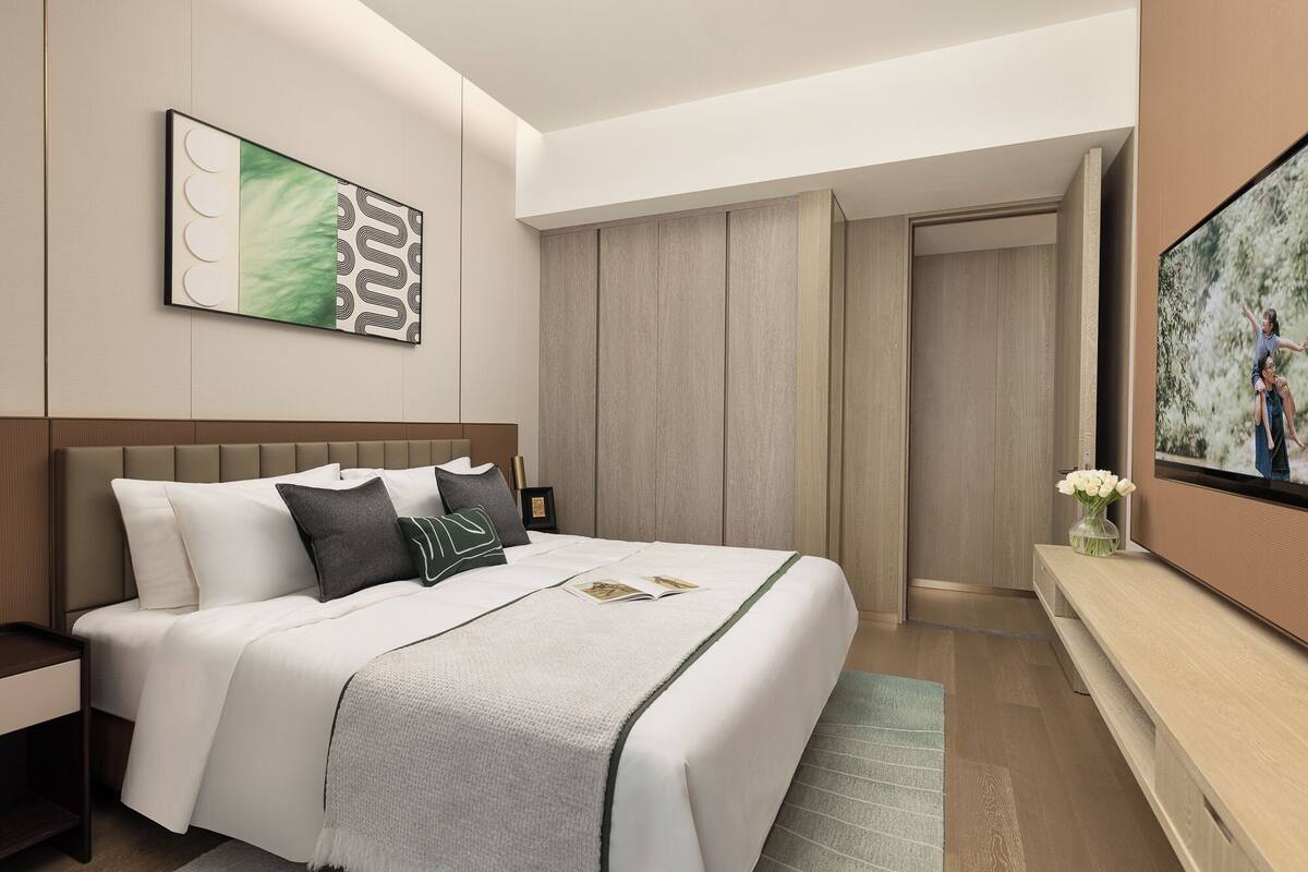 A modern hotel room with a large bed, a nightstand, a wall-mounted TV, and a door leading to another room.