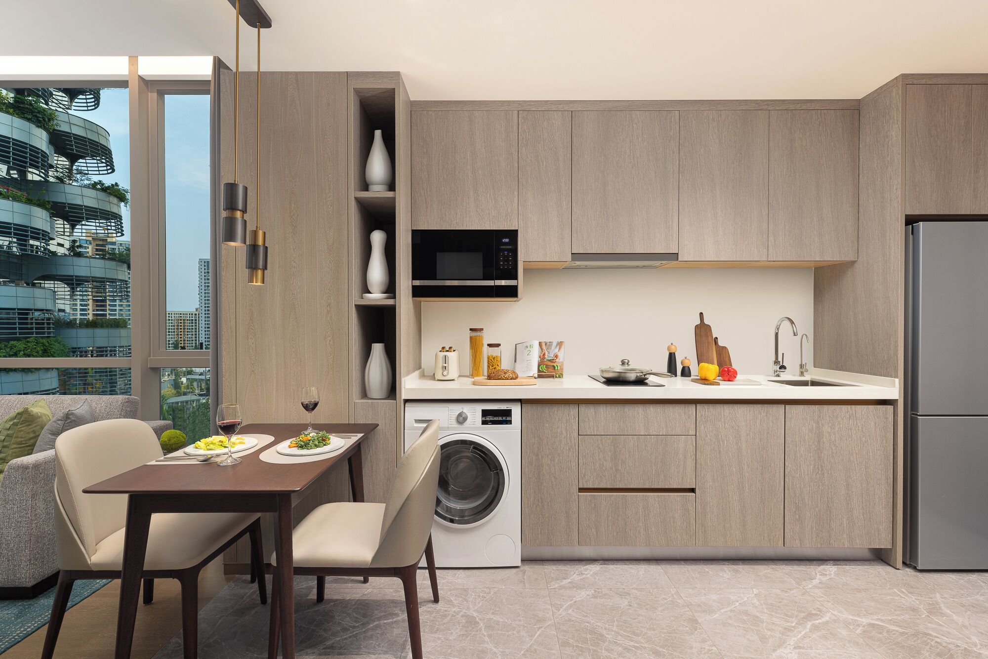 A modern kitchen with a built-in washing machine, a microwave, and a stainless steel refrigerator.