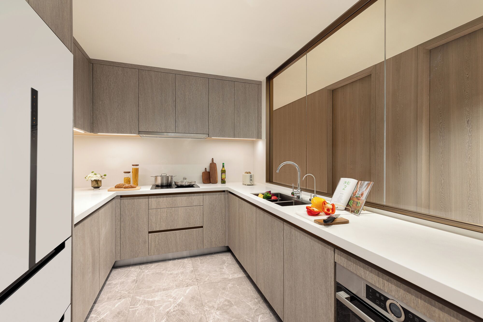 A modern kitchen with grey cabinetry, a white countertop, and a built-in oven.