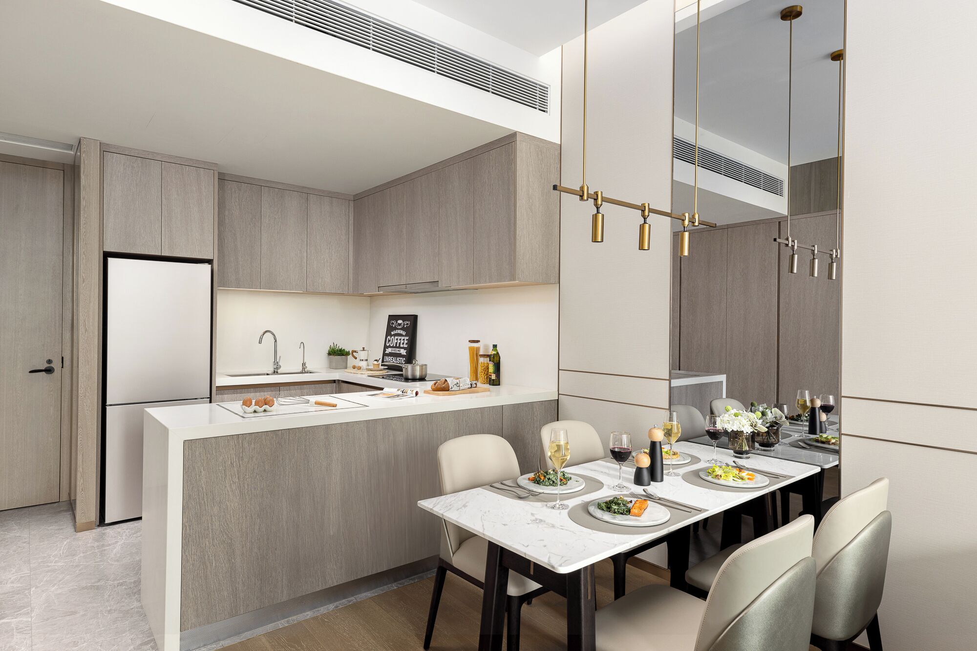 A modern kitchen with a central island, built-in appliances, and a dining area with a marble table and chairs.