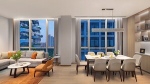 A modern living room with a sofa, coffee table, and dining area with chairs. - Somerset Qplex Shenzhen (Shenzhen)