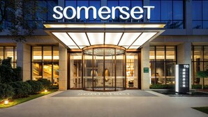 A modern hotel entrance with a revolving door, glass facade, and illuminated signage. - Somerset Qplex Shenzhen (Shenzhen)