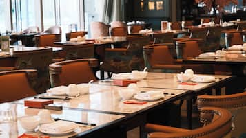 A restaurant with multiple tables set for dining, each with white bowls, plates, and napkins.