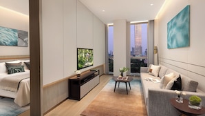 A modern living room with a flat-screen TV, a sofa, a coffee table, and a view of a cityscape through large windows. - Somerset Qplex Shenzhen (Shenzhen)