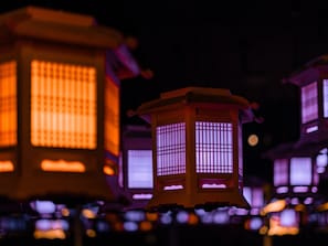 A row of traditional lanterns with a grid pattern, illuminated from within, suggesting a cultural or historical setting. - Giraffe Tenjin Tsune (Fukuoka)