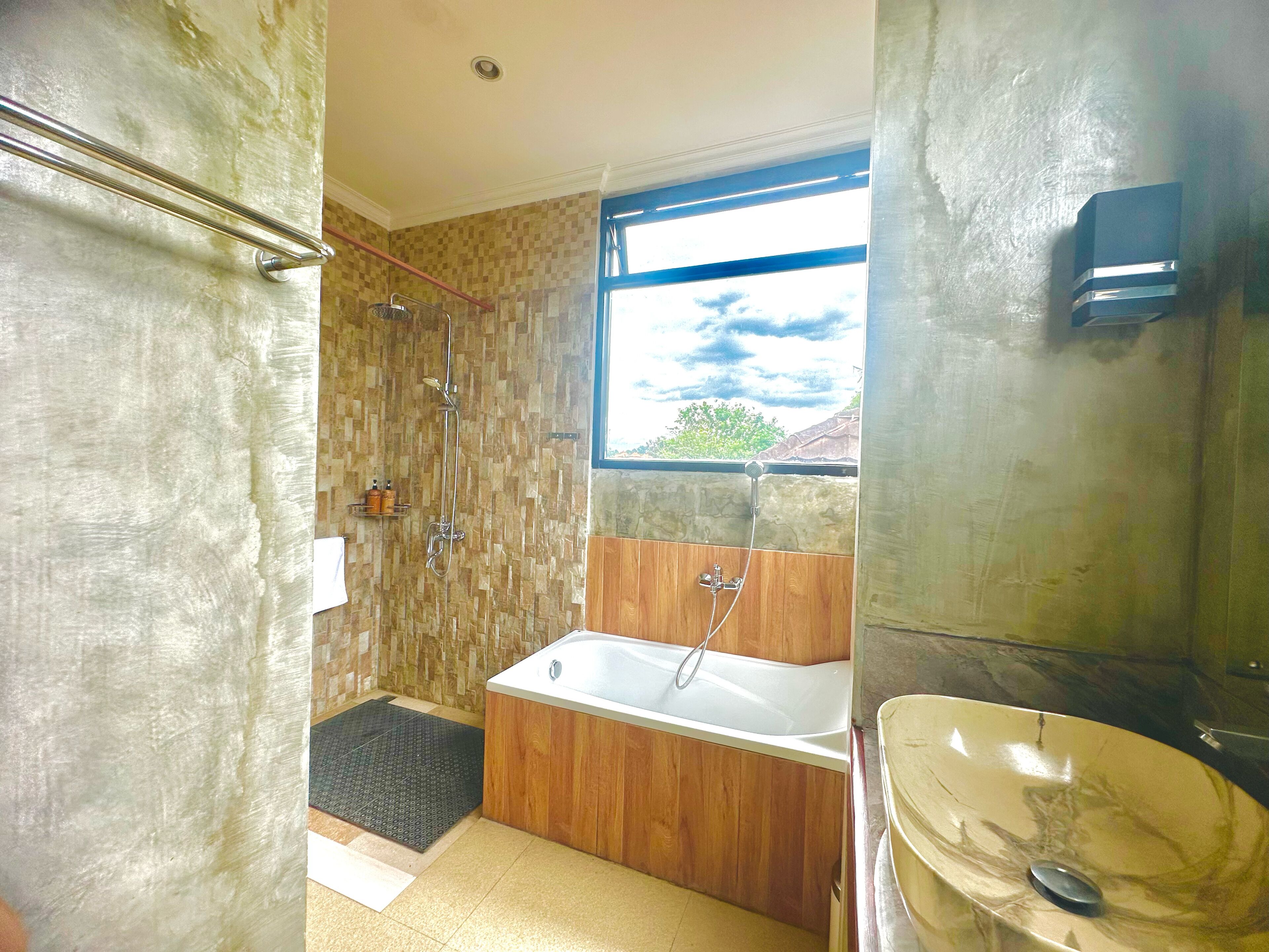 A bathroom with a wooden vanity, a bathtub, and a shower area.