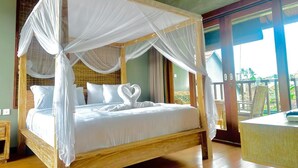 A four-poster bed with white linens and a canopy, a wooden headboard, and a heart-shaped towel decoration. - Mandala Homestay  (Ubud)