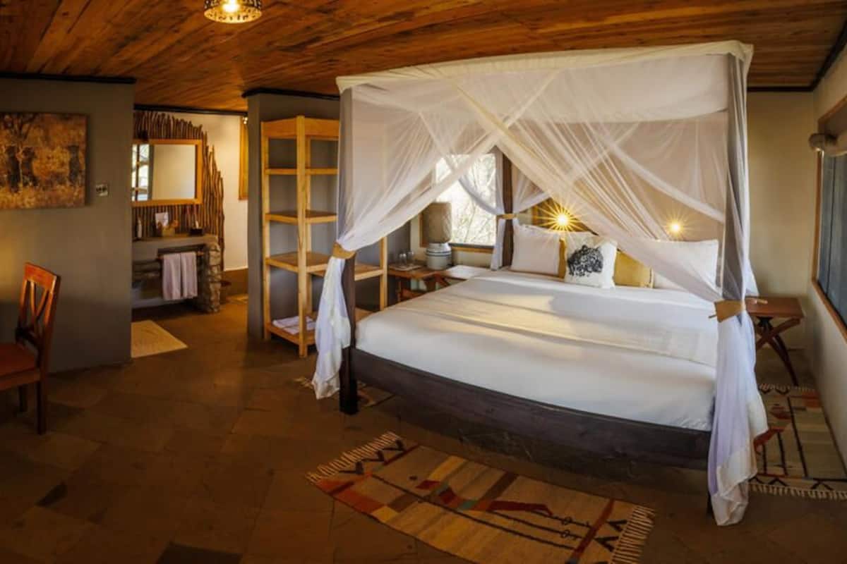 Ein Schlafzimmer mit Himmelbett, Schreibtisch und Stuhl sowie einem Bücherregal.