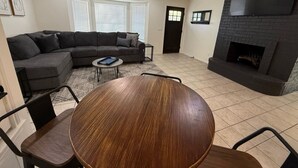 A modern living room with a sectional sofa, a round wooden dining table, and a fireplace. - The Hidden Cove on the Horseshoe (Canyon Lake)