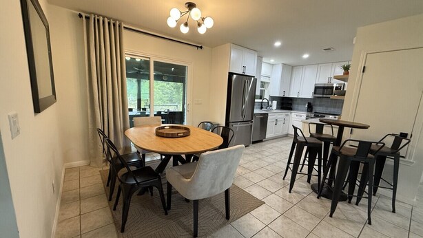 A modern kitchen with a dining area, featuring a round wooden table, chairs, and a built-in oven. - The Hidden Cove on the Horseshoe (Canyon Lake)