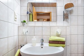A bathroom with a sink, mirror, towel rack, and a small potted plant.