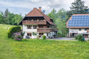 A two-story house with a sloped roof, a balcony, and a solar panel on the right.
