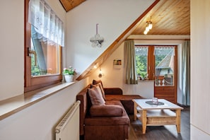 A cozy room with a brown sofa, a small table, and a window with curtains.