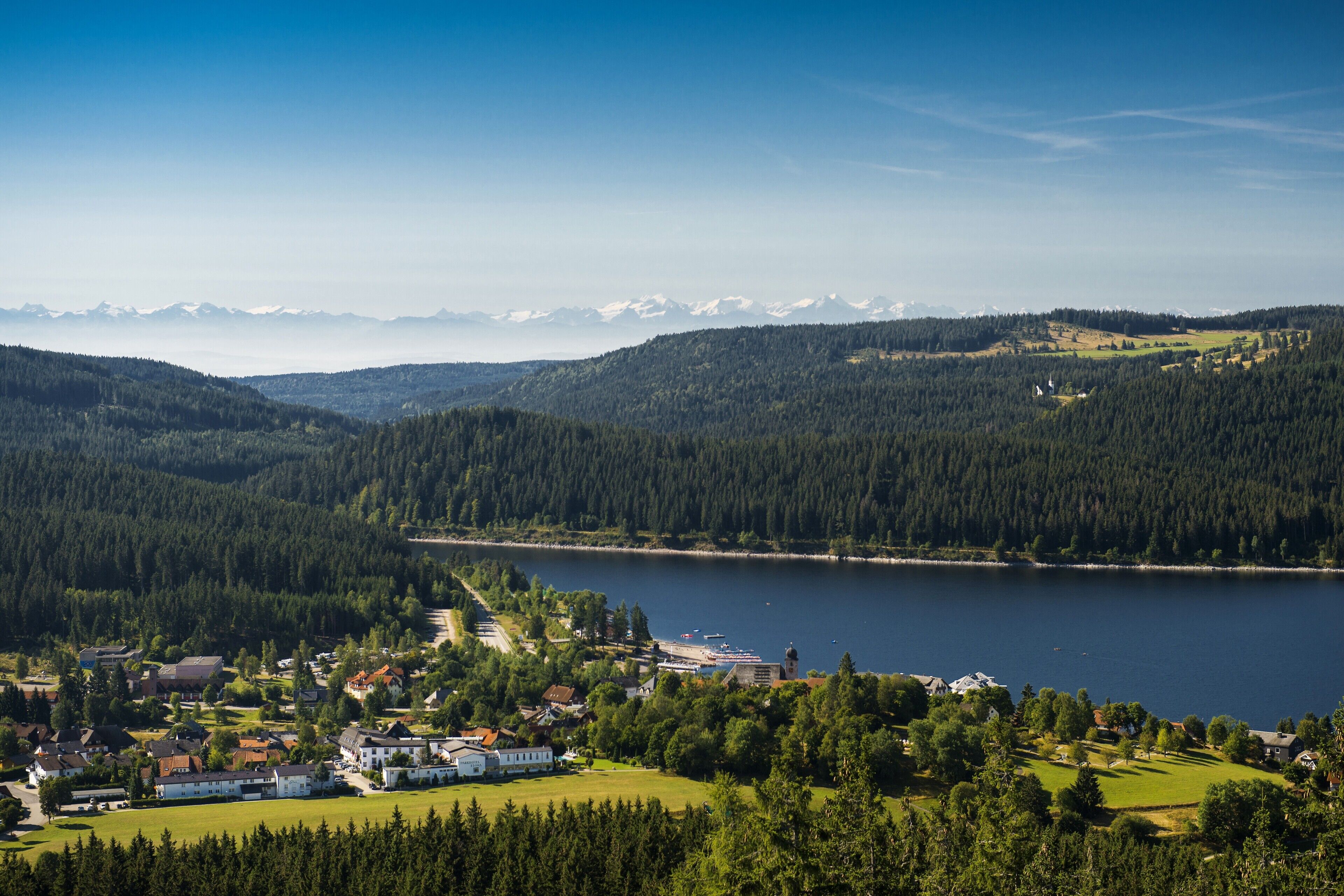 Ein Dorf am See mit Häusern, einer Kirche und Blick auf die Berge.