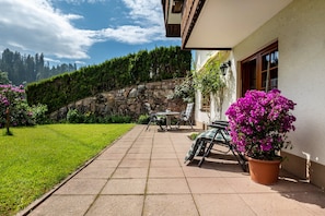 Une terrasse avec un mur en pierre, une table et des chaises, et une plante en pot.
