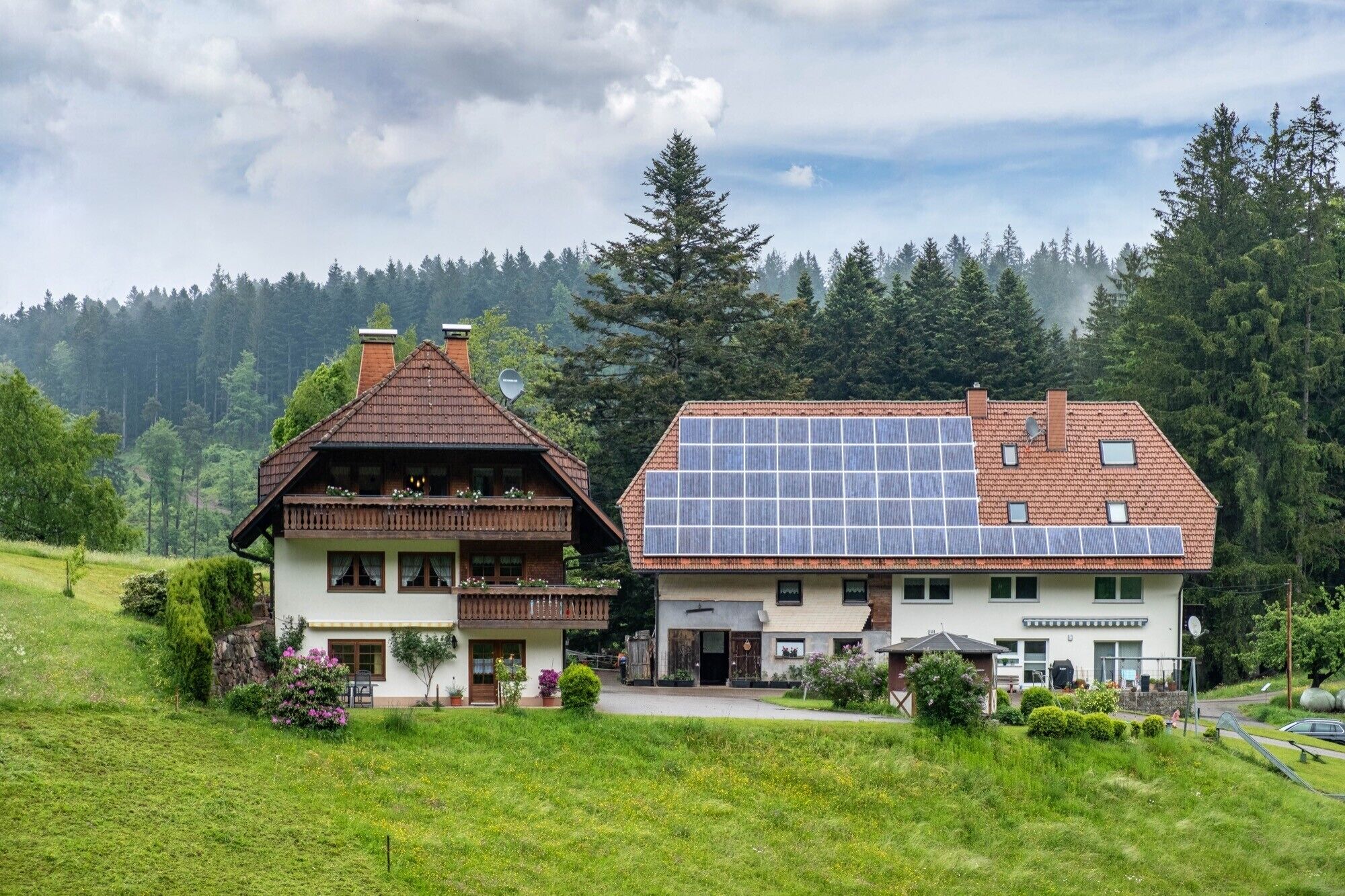A traditional chalet with a sloped roof and a modern building with solar panels.