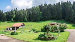Ländliche Landschaft mit Scheune, Schaukel und Garten.