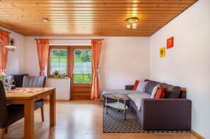 Une pièce avec un plafond en bois, un canapé, une table et une fenêtre avec des rideaux.
