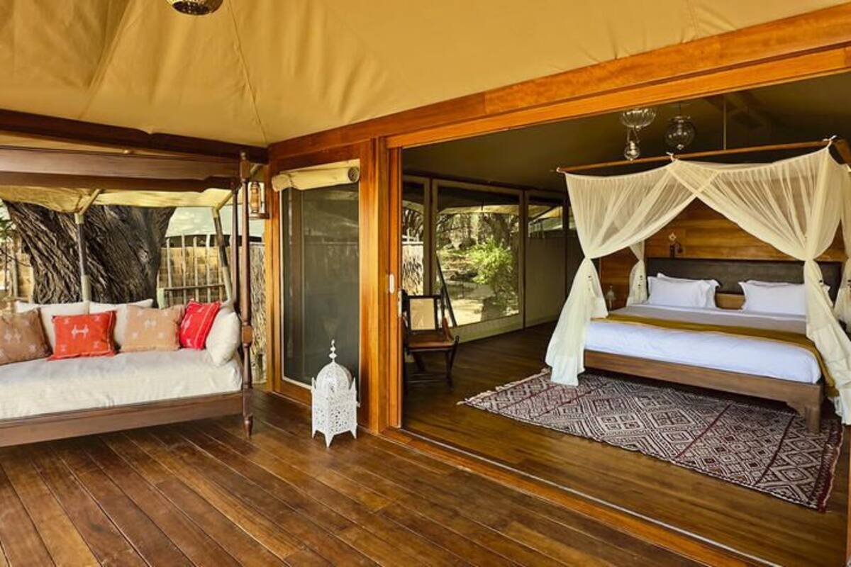 A wooden deck with a sofa and a bed with a canopy.