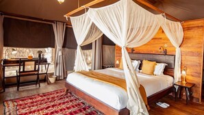 Un dormitorio amplio con cama con dosel, un escritorio con silla y un ventanal grande.
