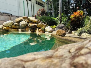 Una piscina cristalina rodeada de rocas y plantas tropicales.