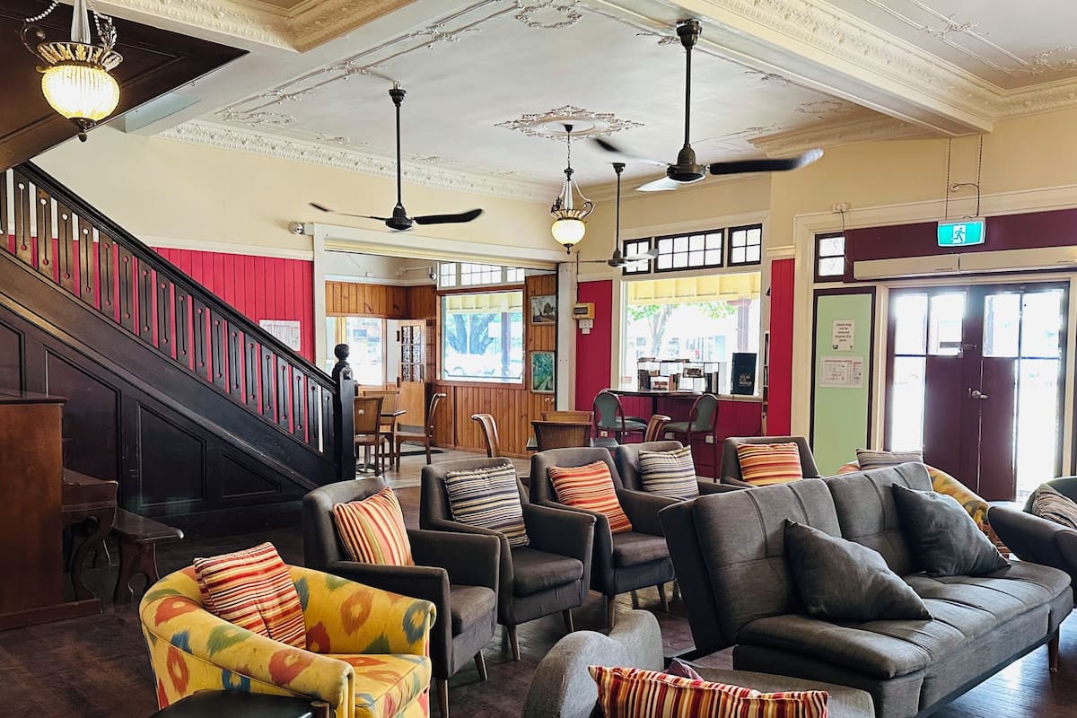 A lobby with a staircase, multiple seating areas, ceiling fans, and a reception desk.