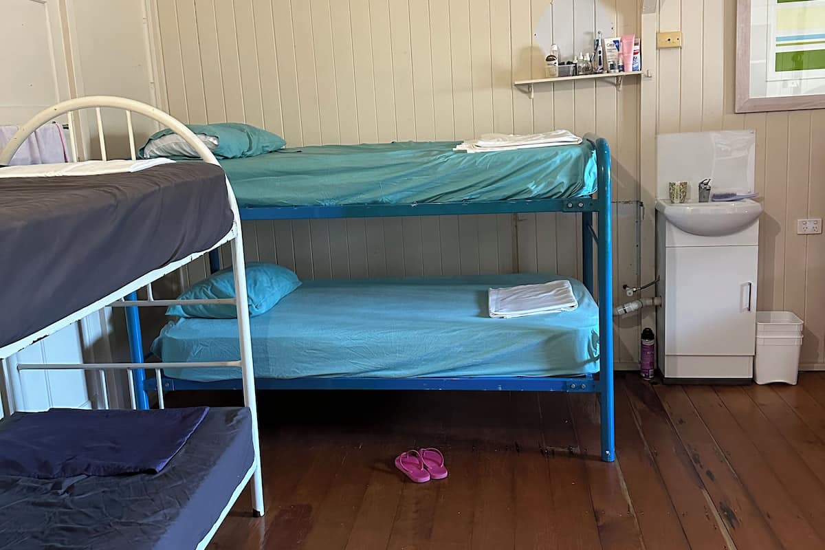 A room with bunk beds, a small sink, and a shelf with toiletries.