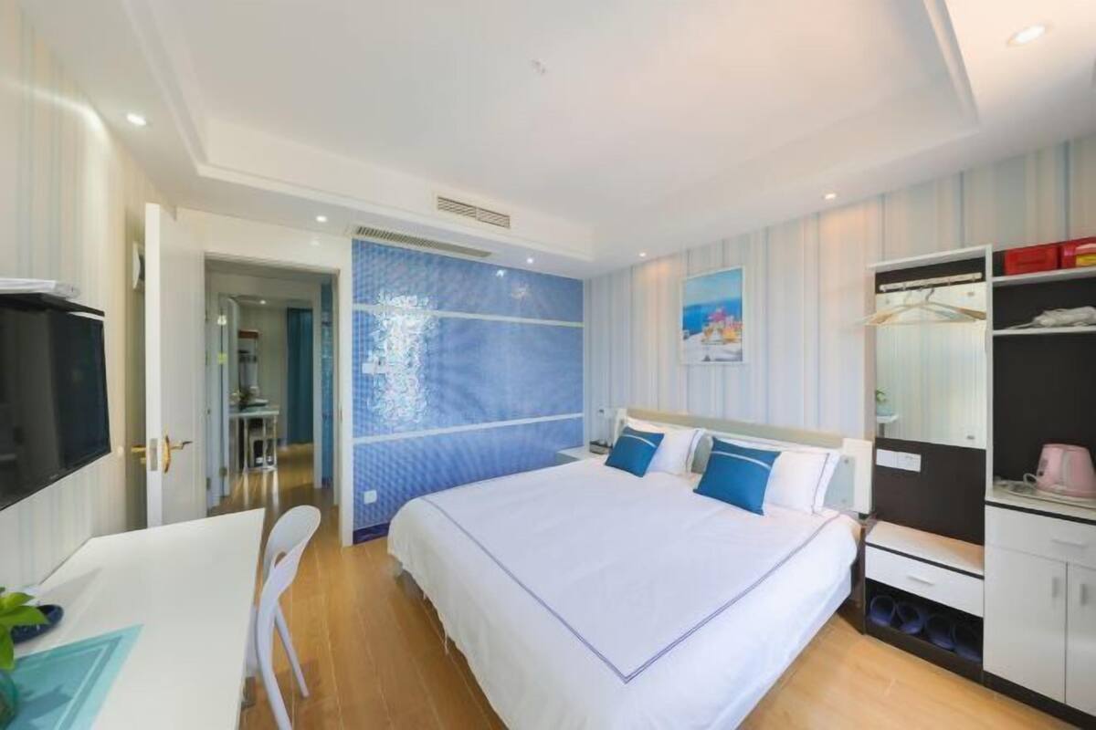 A hotel room with a bed, a desk, a chair, a wardrobe, and a TV.