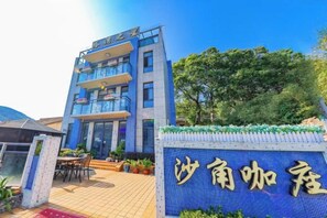 A hotel with a blue facade, a sign with Chinese characters, and a tiled entrance area.