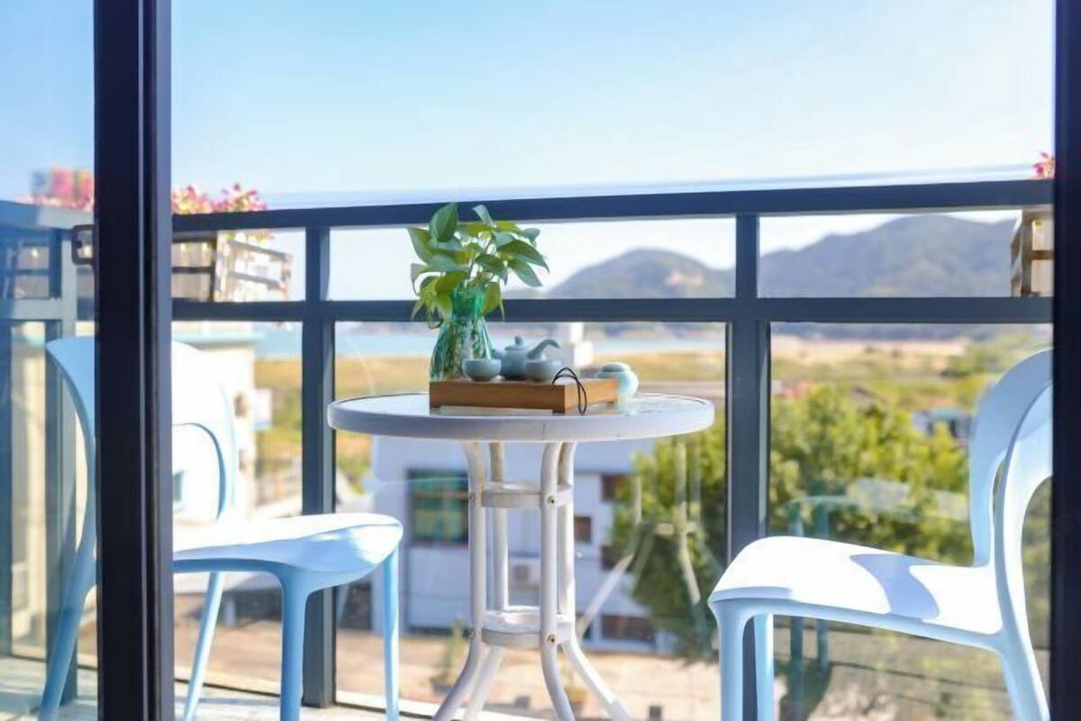 A balcony with a table, chairs, and a potted plant.