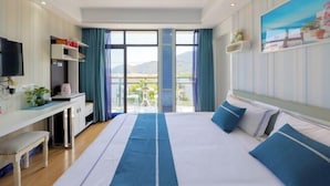 Habitación de hotel con cama, escritorio, televisor y balcón con vistas.