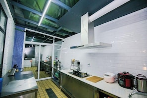 Una cocina con encimera de acero inoxidable, cocina a gas, cafetera y hervidor eléctrico rojo.