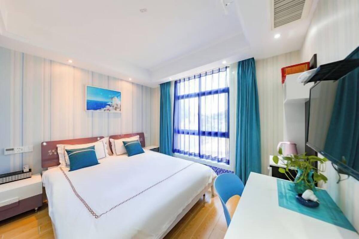 A hotel room with a large bed, a desk, and a window with curtains.