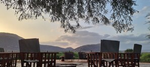 A terrace with wooden chairs and tables, overlooking a mountainous landscape. - Soroi Samburu Lodge (Samburu)