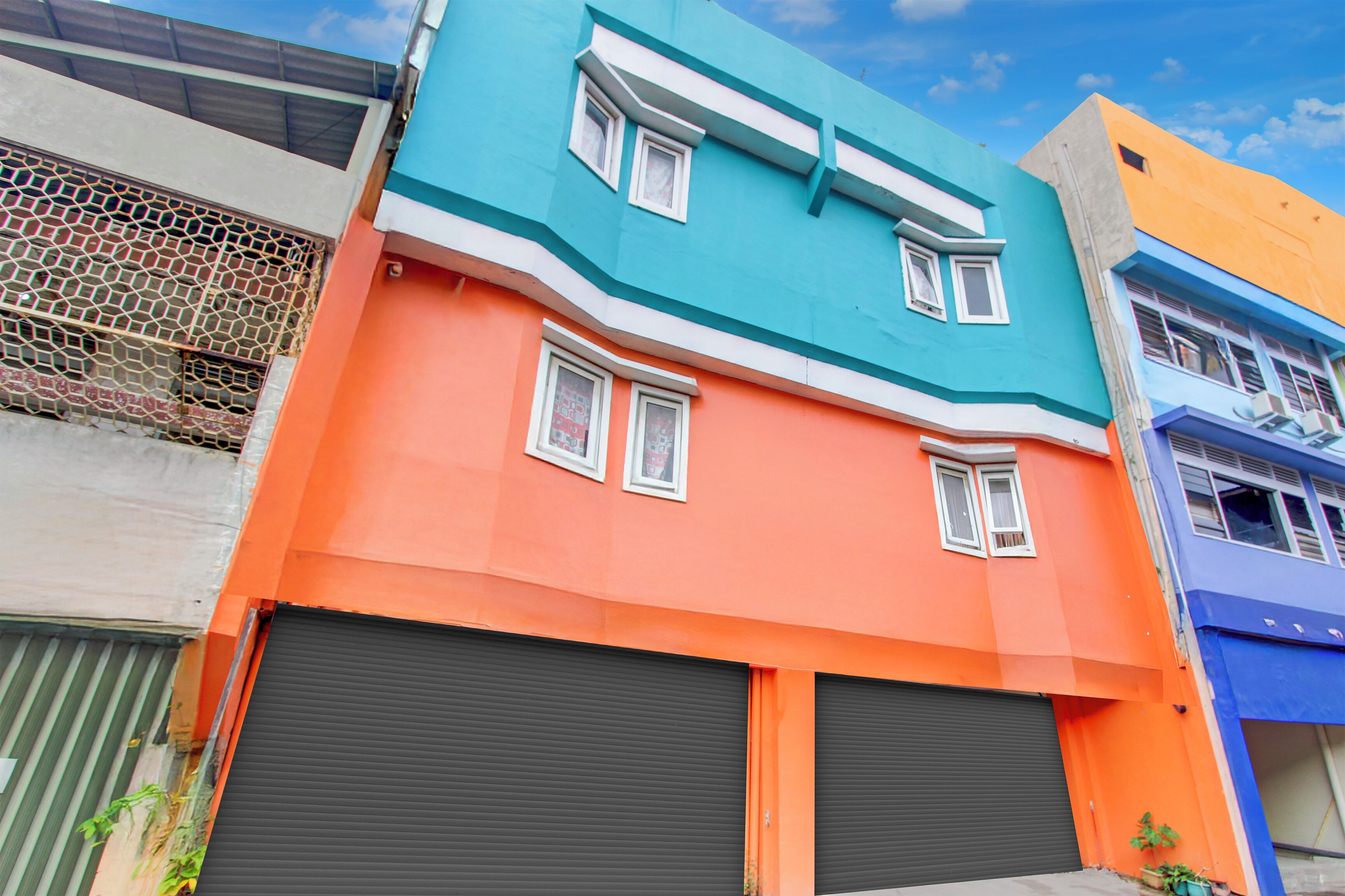 Un edificio a più piani con tetto piatto, due finestre visibili al secondo piano e un'ampia porta garage al piano terra.