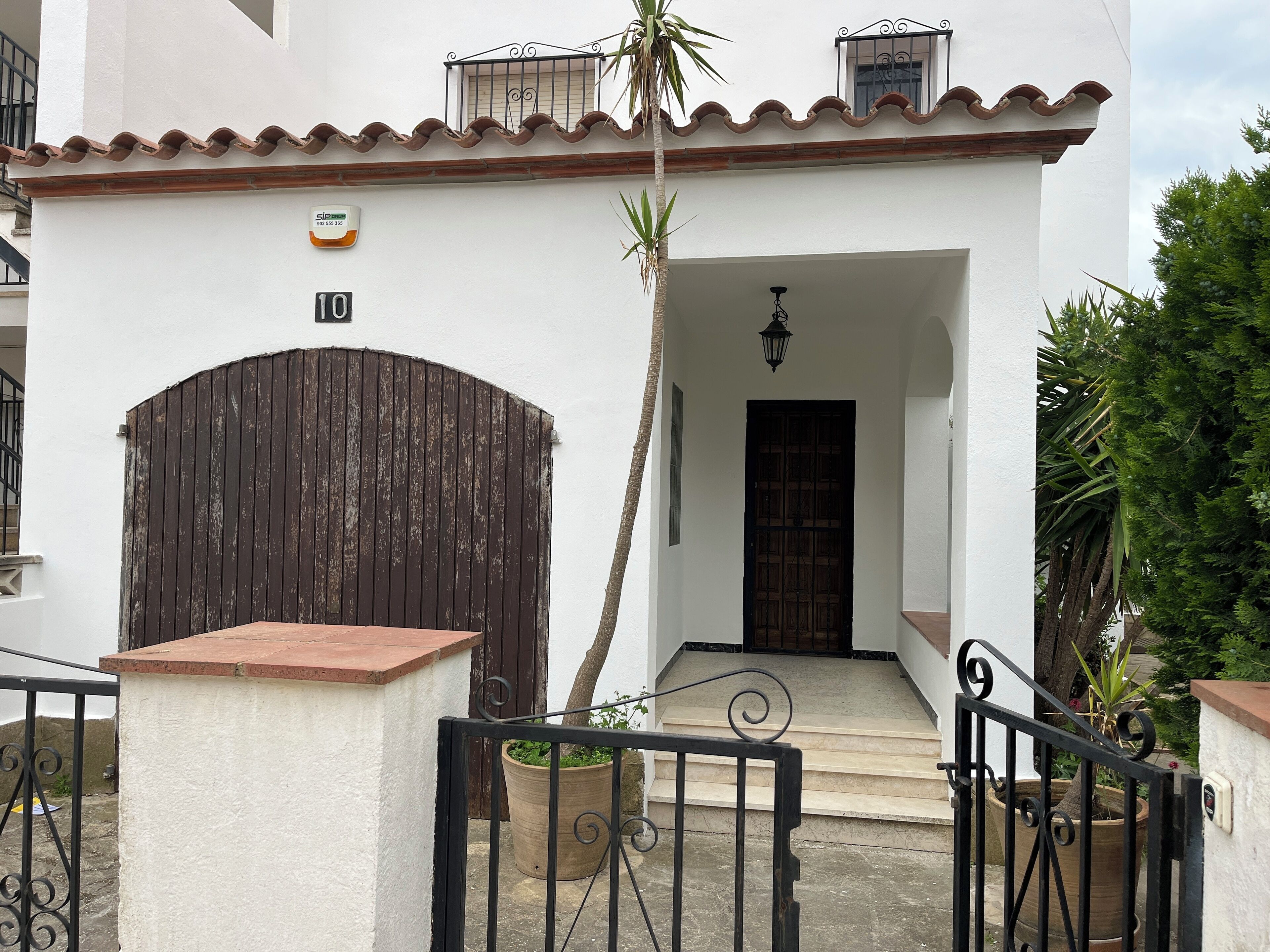 A white building with a brown door and a number '10' sign.