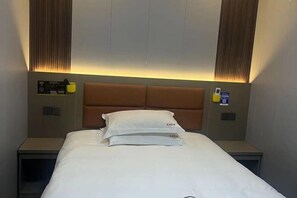 A hotel room with a bed, headboard, nightstands, and a wall-mounted control panel.