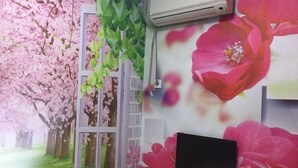 Habitación con un mural de flores de cerezo y una ventana con marco blanco.