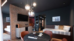 Ein modernes Wohnzimmer mit Kamin aus Backstein, einem runden Tisch mit Stühlen, einer Couch und einem an der Wand befestigten Fernseher.