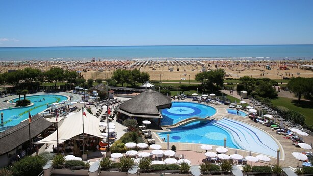 A resort with multiple swimming pools, beach areas, and outdoor seating.