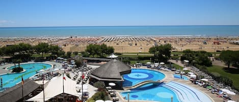 Resort com várias piscinas, áreas de praia e assentos externos.