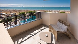 A balcony with a view of a beach and a swimming pool.