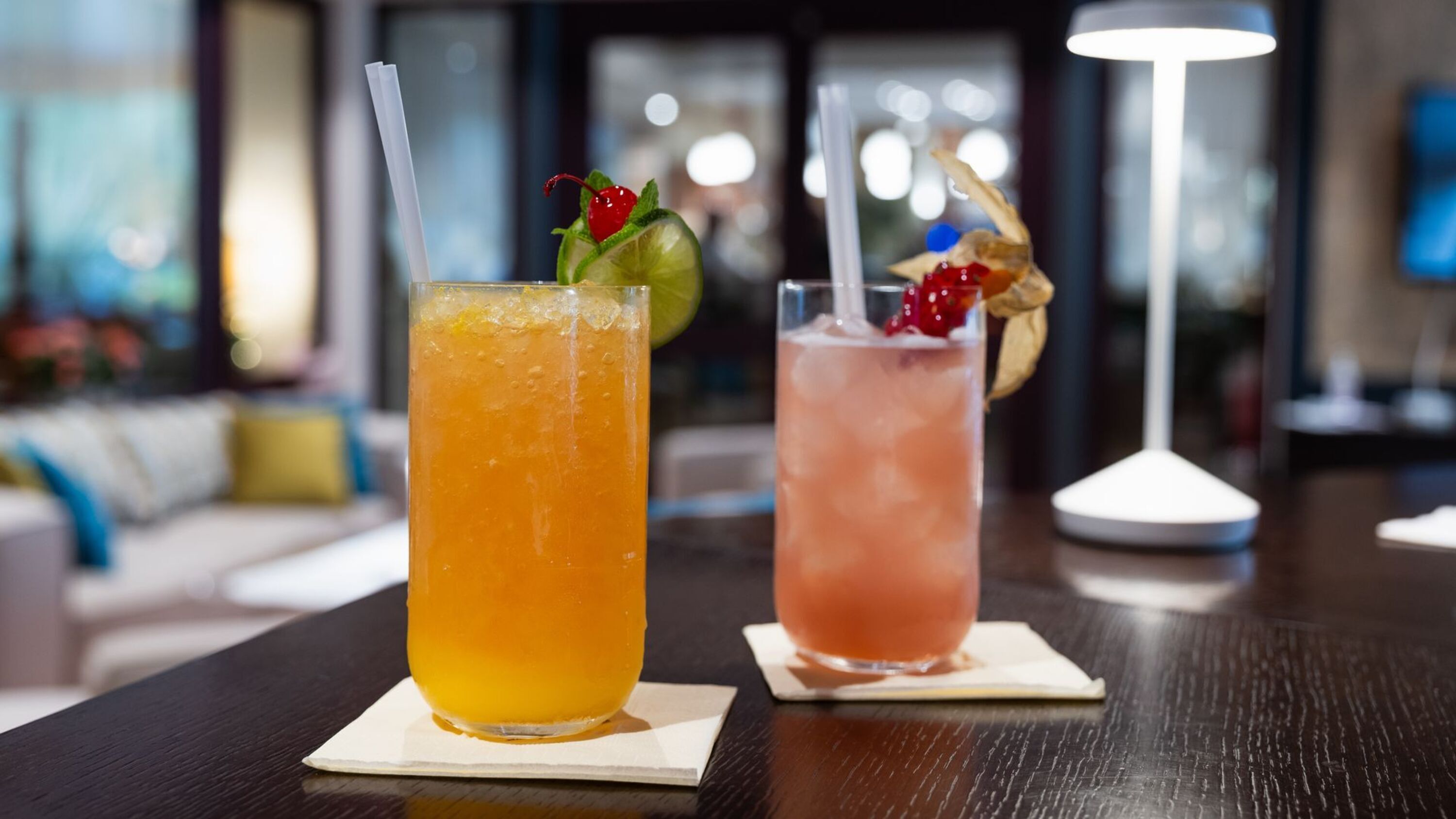 Zwei Cocktails auf einem Tisch, moderne Inneneinrichtung im Hintergrund.