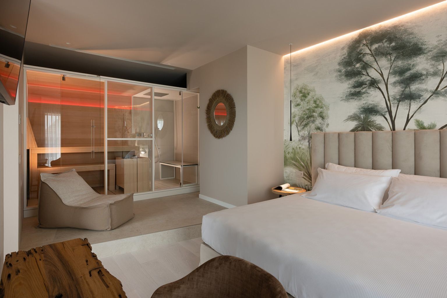Un dormitorio moderno con una cama grande, un vestidor con puertas de vidrio y un espejo adosado a la pared.