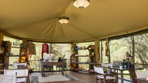 A tented accommodation with a wooden table, chairs, and a laptop. - Soroi Private Camp (Maasai Mara)