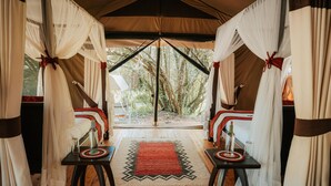 A tented room with two beds, a red rug, and a view of trees outside. - Soroi Private Camp (Maasai Mara)