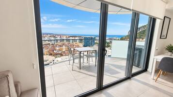 Un apartamento moderno con un gran ventanal corredero que da a un balcón con vistas a la ciudad.