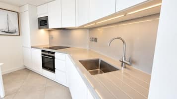 A modern kitchen with white cabinetry, a stainless steel sink, and a built-in oven.